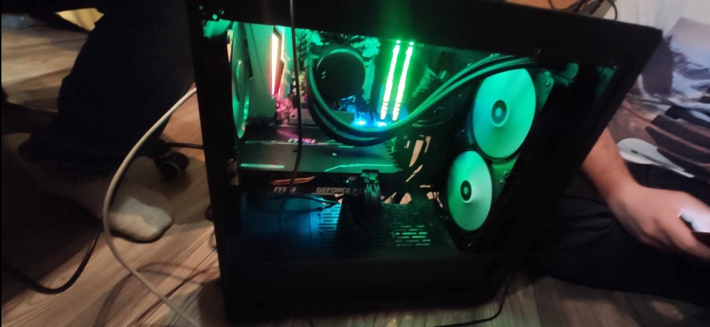 Otwarta obudowa komputera stacjonarnego z podświetleniem LED w kolorze zielonym i białym, widoczne wentylatory, karta graficzna MSI GeForce RTX. Komputer po naprawie.