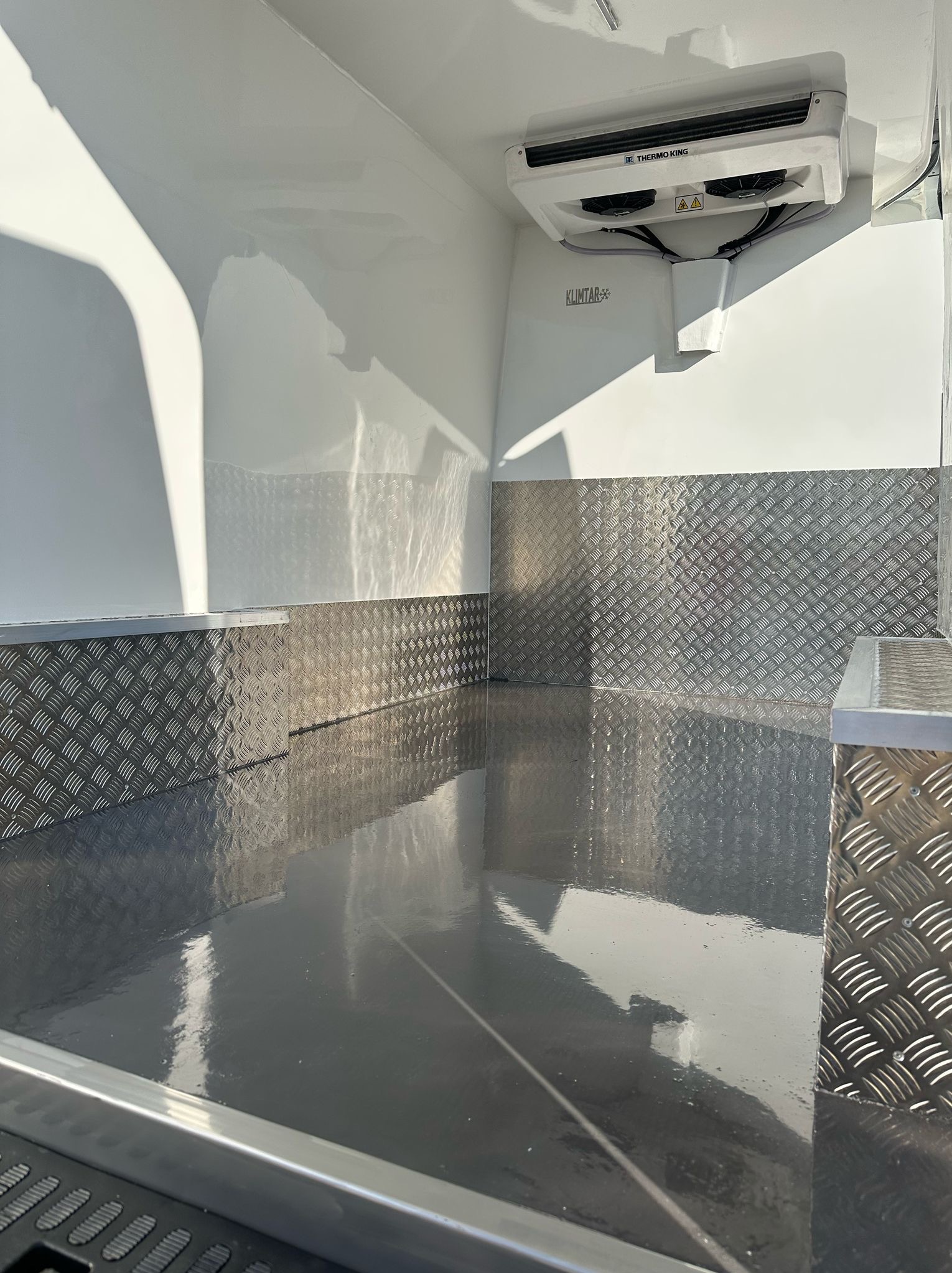 Wnętrze chłodni samochodowej z zamontowanym agregatem Thermo King i aluminiową blachą ryflowaną na ścianach.