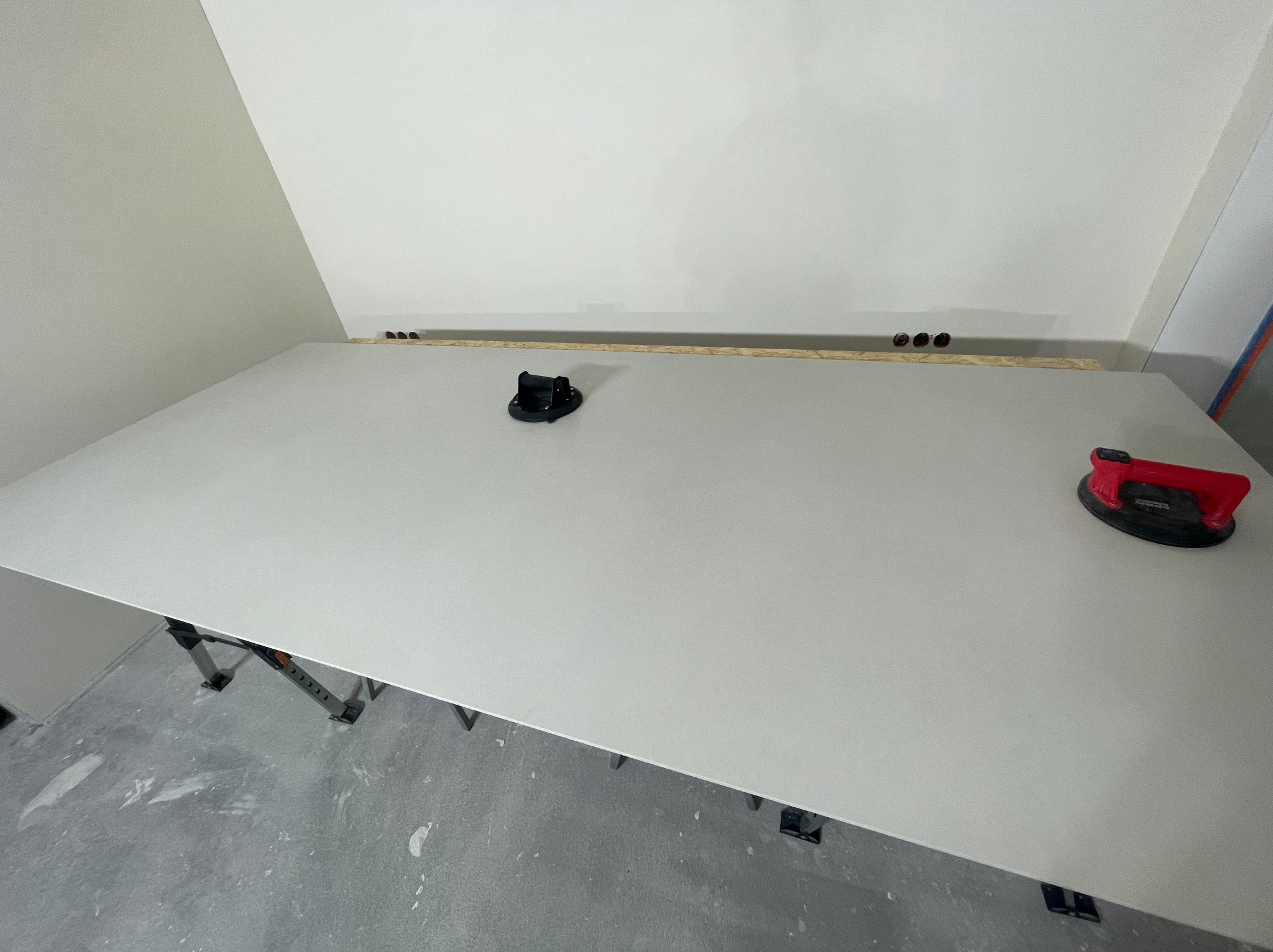 Płyta gipsowa na stelażu, przygotowana do montażu na skośnej ścianie poddasza. Widoczne przyssawki do przenoszenia i otwory na instalację elektryczną.