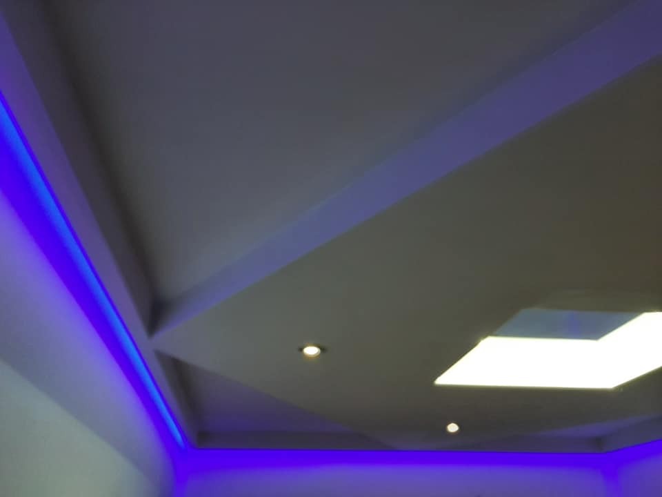 Podwieszany sufit z oświetleniem LED w kolorze niebieskim i punktowymi lampami, widok z dołu, nowoczesny design.