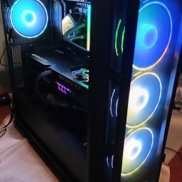 PeCEnter IT - Złożony, gamingowy PC w czarnej obudowie z przeszklonym bokiem, podświetlany wentylatorami RGB. Widoczna karta graficzna MSI GeForce RTX i chłodzenie wodne.