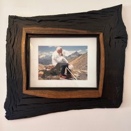 WOODEN ART SPÓŁKA Z OGRANICZONĄ ODPOWIEDZIALNOŚCIĄ - Ręcznie wykonana rama z ciemnego drewna otaczająca zdjęcie górskiego krajobrazu z siedzącą osobą, unikalna faktura drewna, naturalny wygląd.