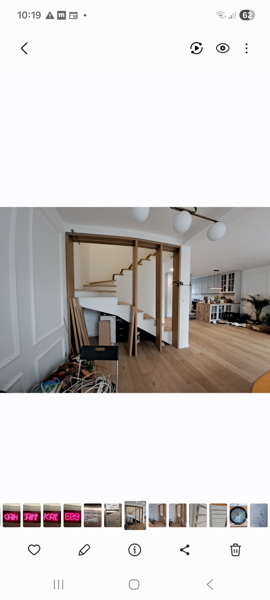 Wnętrze domu w trakcie budowy schodów z drewnianymi elementami. Widoczne przygotowane deski i konstrukcja schodów na tle jasnego pomieszczenia z drewnianą podłogą.