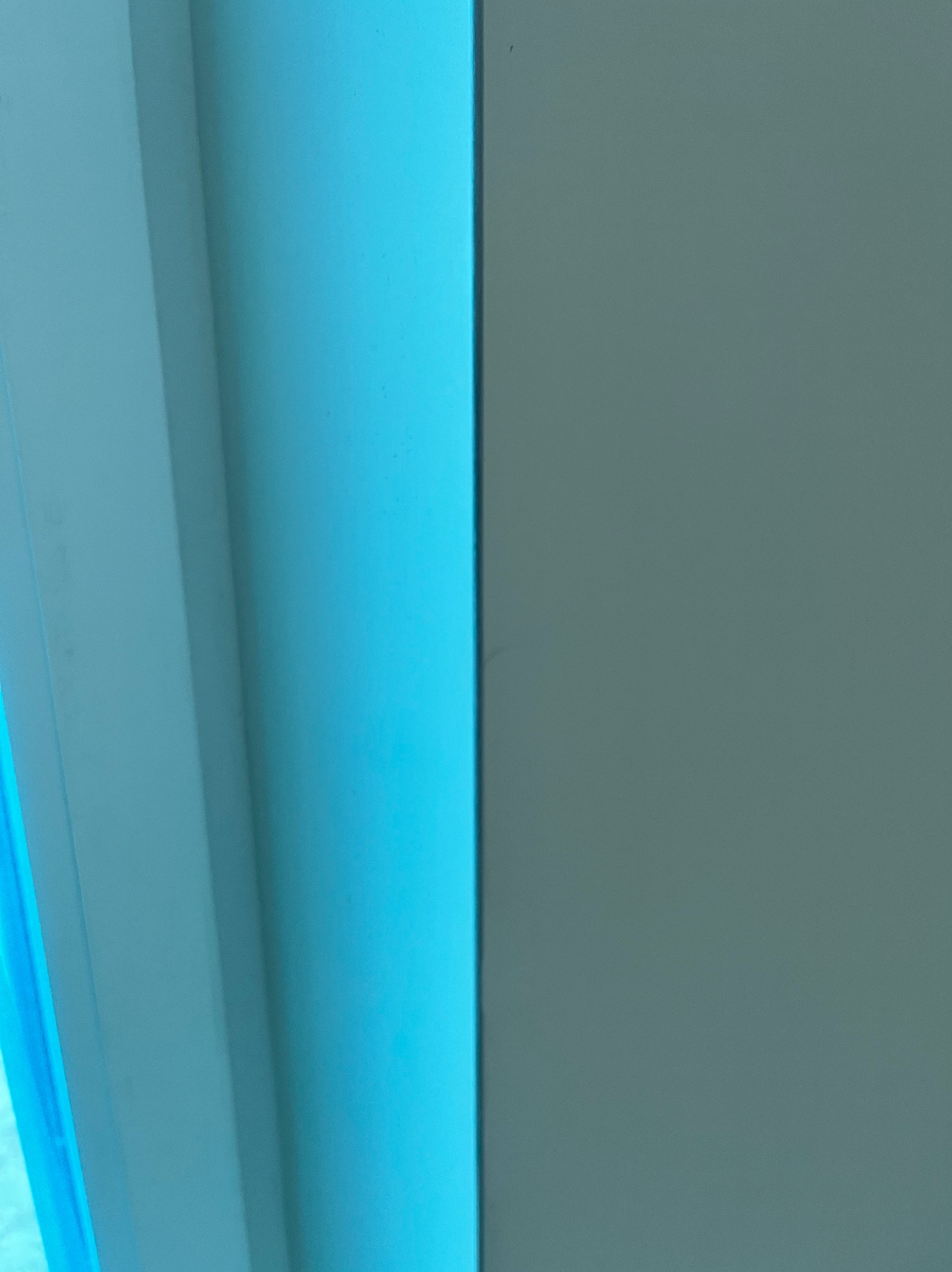 Świeżo pomalowana, gładka ściana w odcieniach błękitu i szarości, z wyraźnie zaznaczonymi krawędziami i subtelnym światłocieniem.