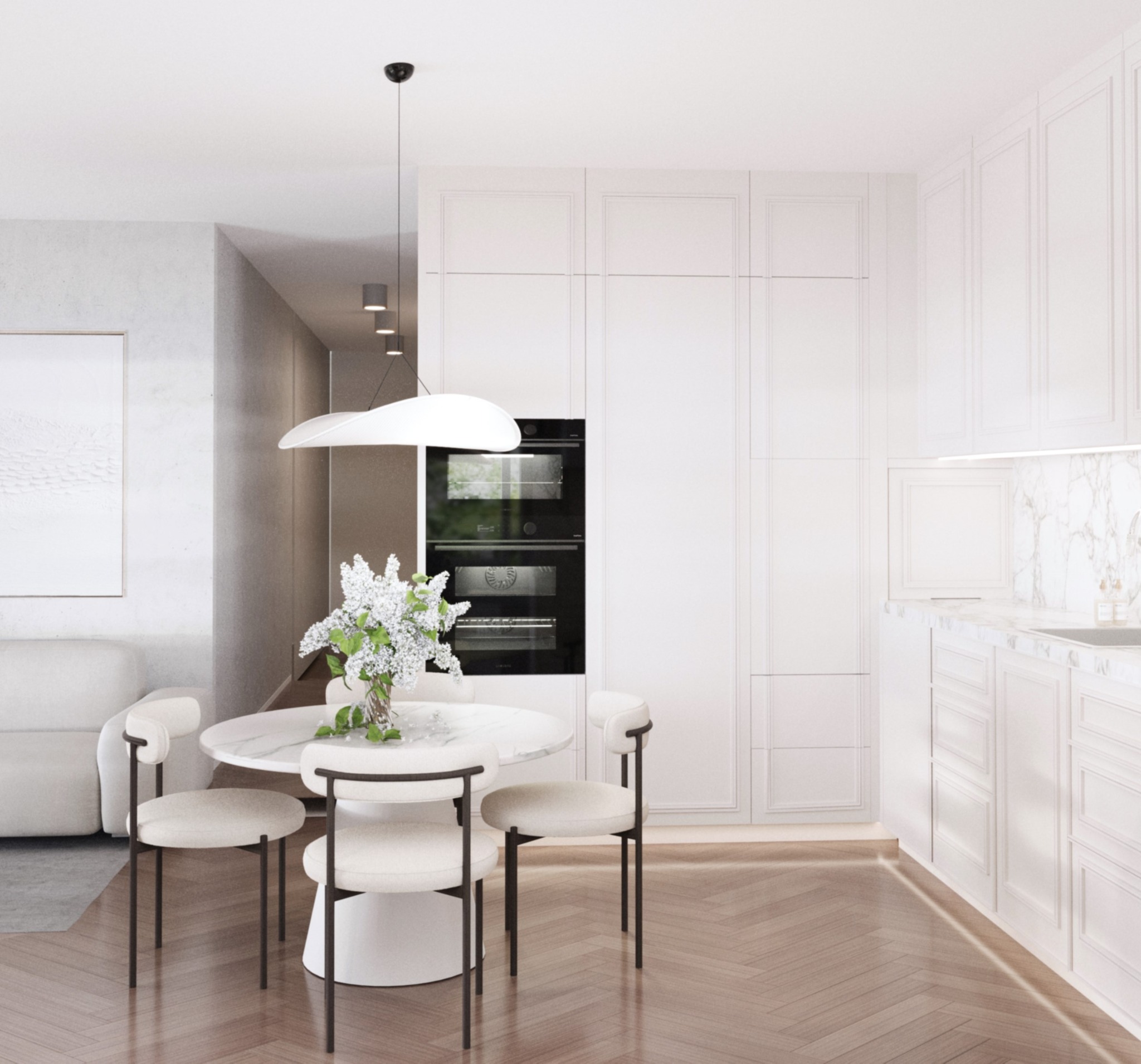 Jasna kuchnia z okrągłym stołem i kwiatami, minimalistyczny design, zabudowa kuchenna z piekarnikiem, parkiet w jodełkę, subtelne oświetlenie.