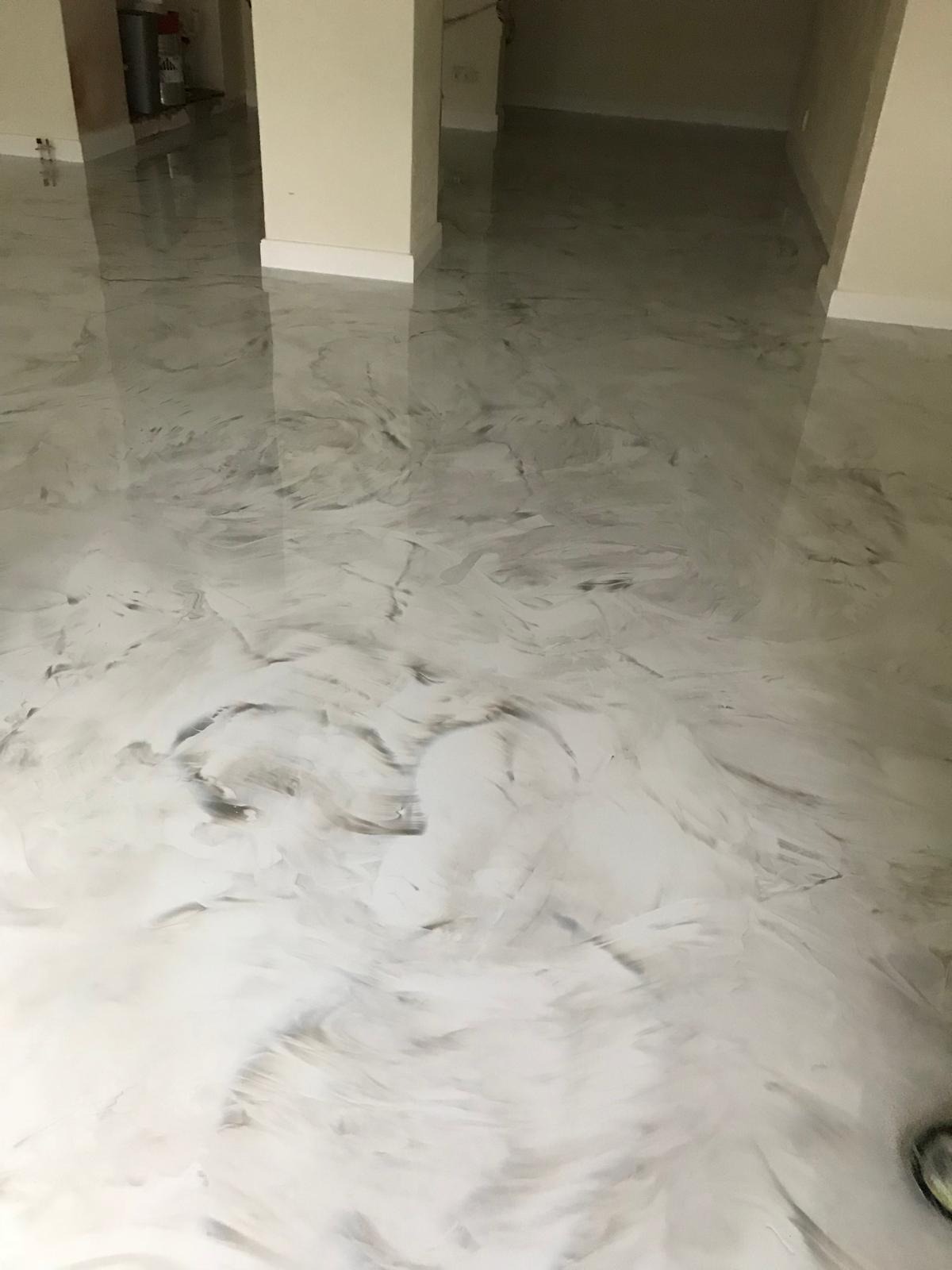 Błyszcząca, jasna posadzka z efektem marmuru w pomieszczeniu z beżowymi ścianami i kolumnami. Widoczne refleksy światła podkreślają gładką powierzchnię.