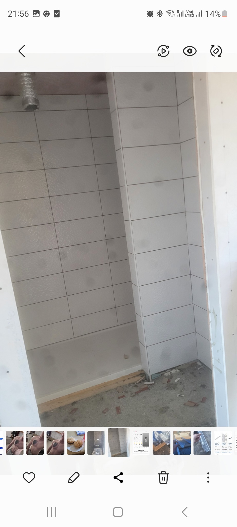 Wnętrze łazienki w trakcie prac wykończeniowych. Widoczne białe płytki na ścianach, surowy beton na podłodze i fragment instalacji wentylacyjnej.