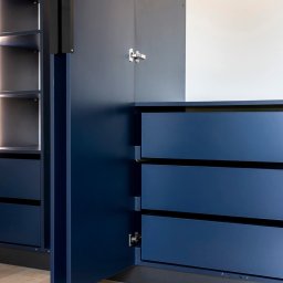 TPMU Agnieszka Rogala - Niebieska szafa wnękowa z oświetleniem LED, widoczne półki i szuflady, otwarte drzwi ukazują wnętrze, minimalistyczny design.