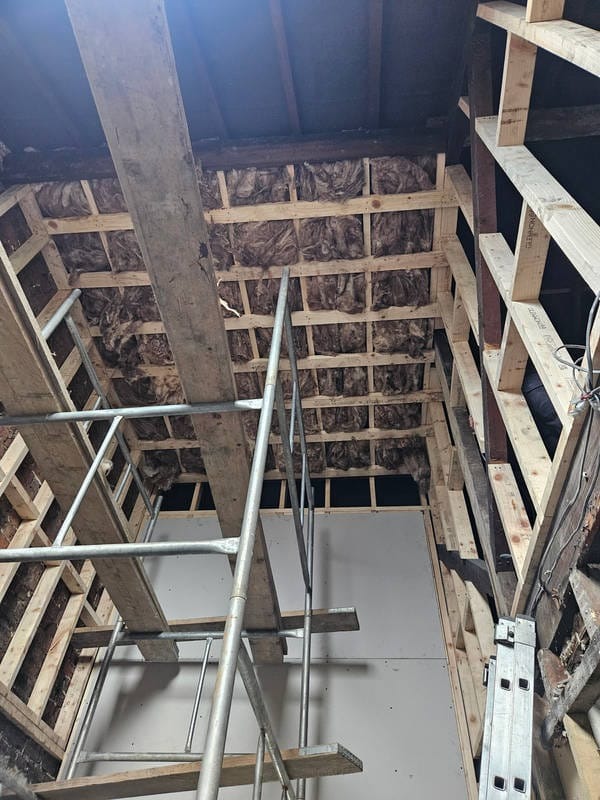 Sufit z izolacją z wełny mineralnej, drewniana konstrukcja szkieletowa, rusztowanie i płyta gipsowa w trakcie montażu. Prace wykończeniowe poddasza.