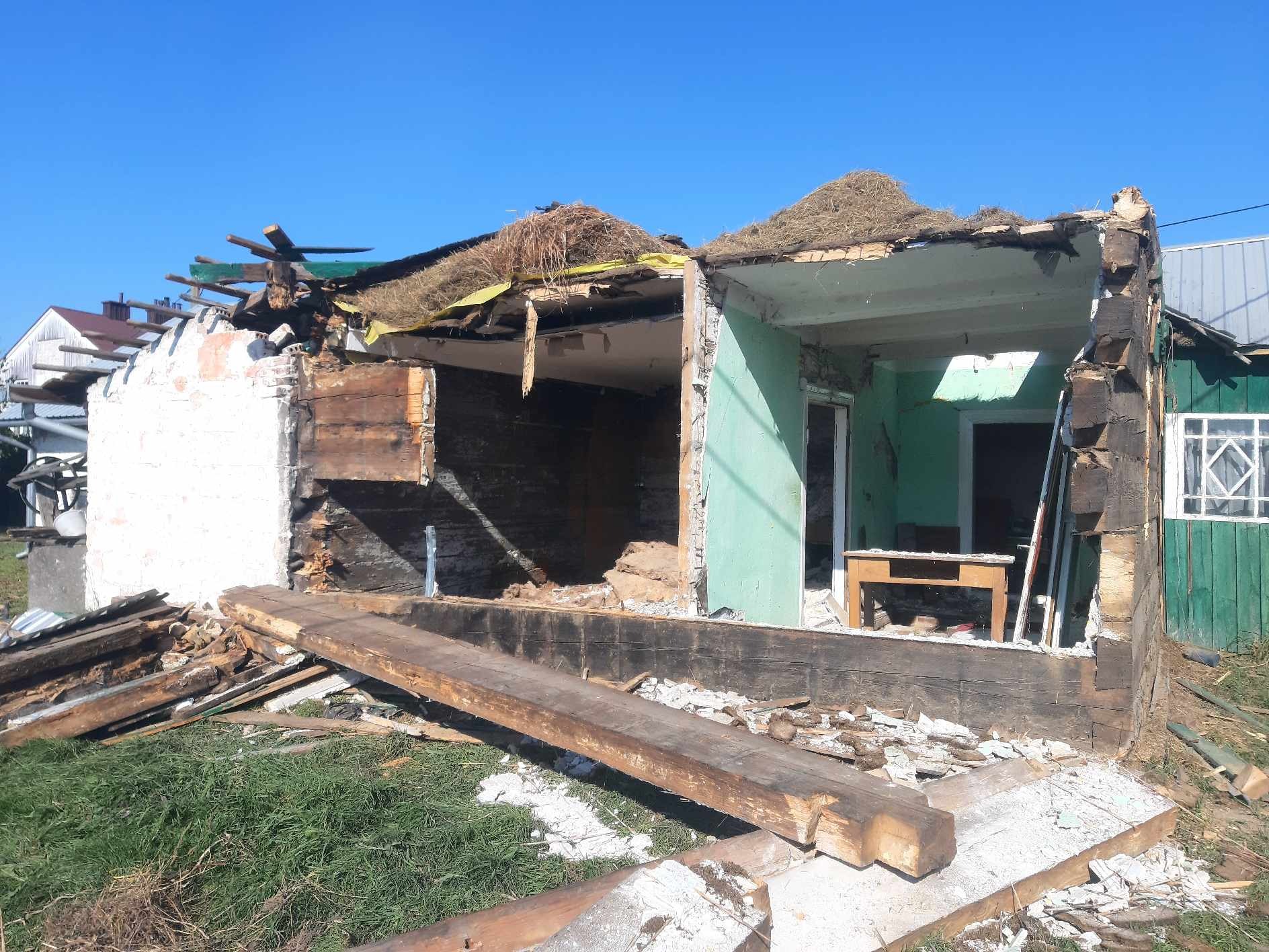 Zdemolowany budynek po rozbiórce w Rzeszowie. Widoczne fragmenty ścian, resztki dachu i gruz. Prace rozbiórkowe w toku, słoneczny dzień, wyraźne ślady zniszczeń.