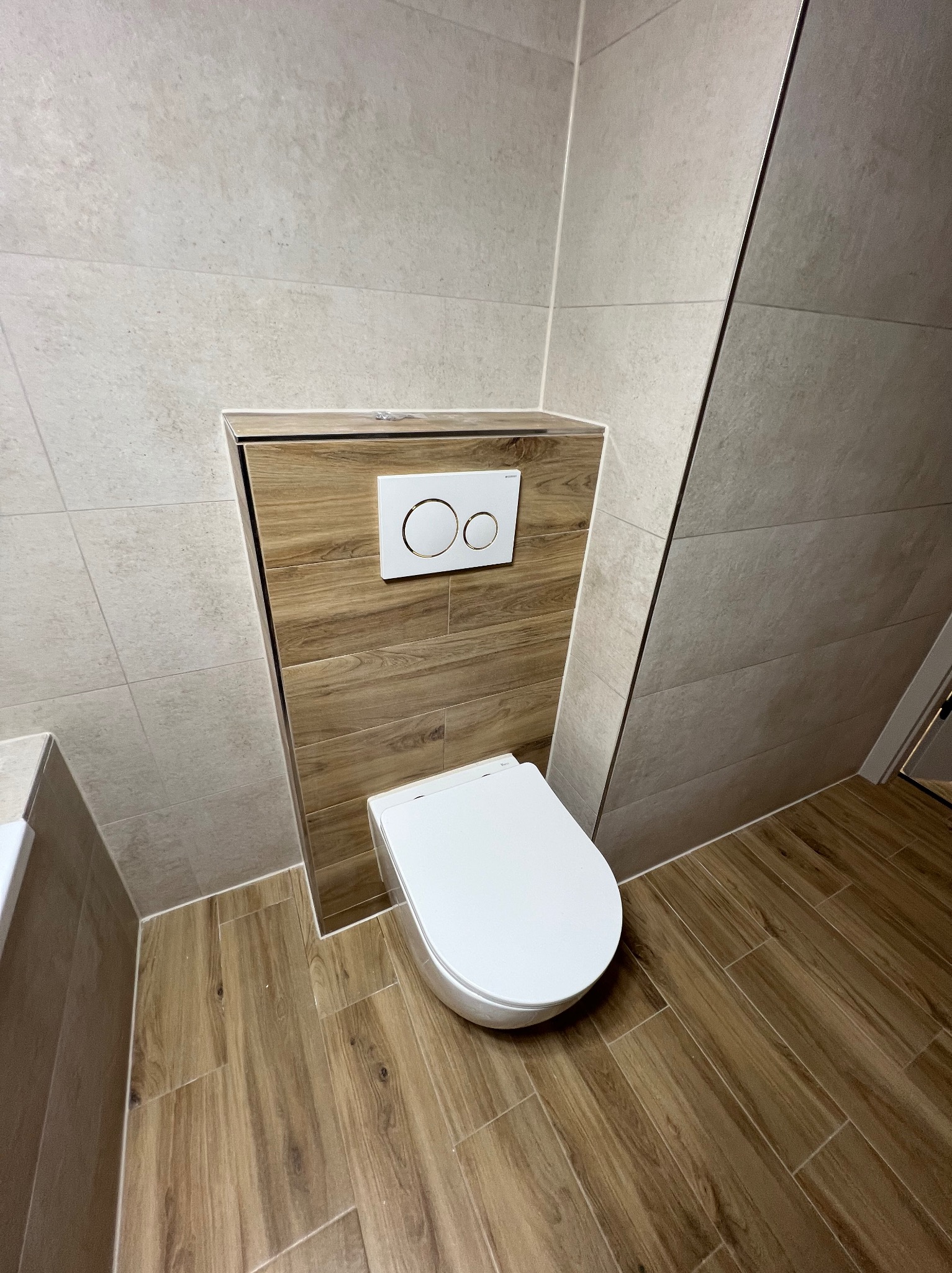 Nowoczesna toaleta z zabudową w drewnopodobnych płytkach, biała ceramika, jasne płytki ścienne i podłogowe, minimalistyczny design, wykończenie łazienki.