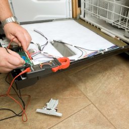 GTX SERVICE SP. Z O.O. SPÓŁKA KOMANDYTOWA - Serwisant w Warszawie diagnozuje usterkę zmywarki za pomocą multimetru. Otwarta obudowa, widoczne przewody i elementy elektroniczne.