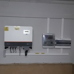 ISKRUS SPÓŁKA Z OGRANICZONĄ ODPOWIEDZIALNOŚCIĄ - Zamontowany inwerter fotowoltaiczny Solis z okablowaniem i licznikiem na ścianie wewnątrz budynku. Widoczne elementy instalacji elektrycznej.