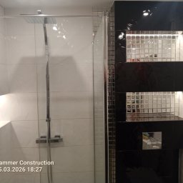 MARIUSZ WÓJCIK Remonty - Nowoczesna kabina prysznicowa z biało-czarnymi płytkami, mozaiką i wnęką z oświetleniem LED. Widoczny deszczownica i bateria. Minimalistyczny design.