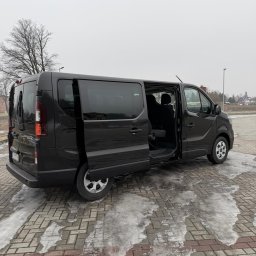 HOME OF LASHES EWELINA OBIREK - Czarny bus z otwartymi drzwiami przesuwnymi na parkingu z resztkami śniegu. Widoczny fragment wnętrza i siedzenia. Pochmurny dzień.