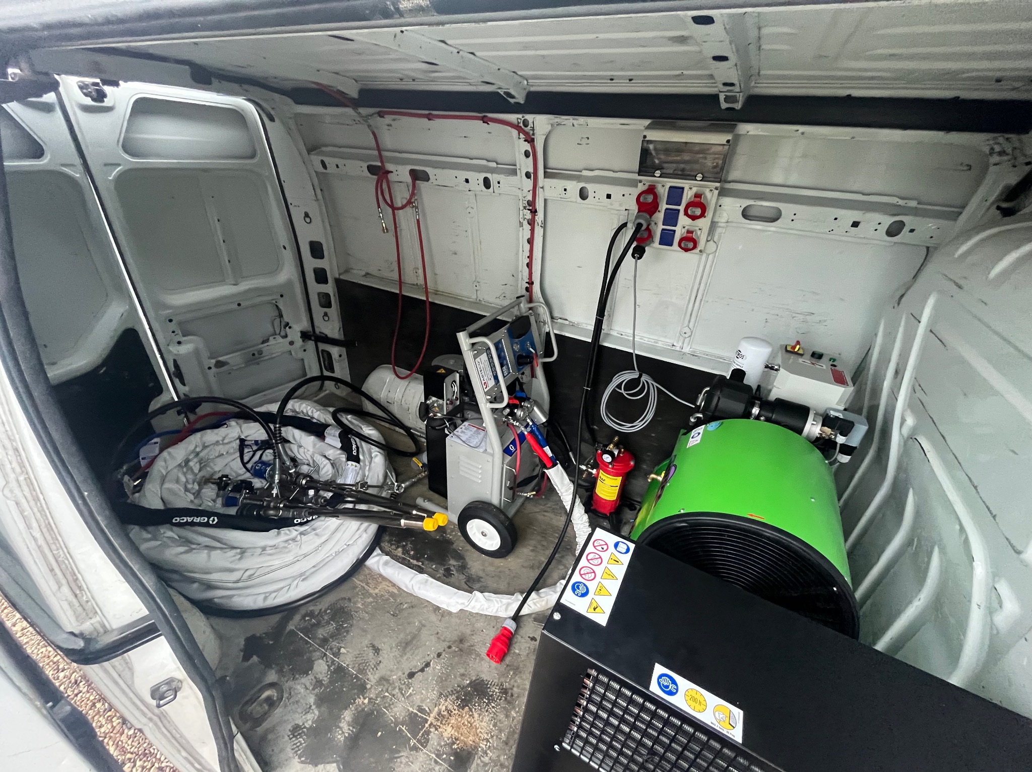 Wnętrze busa z profesjonalnym sprzętem do ocieplania pianką PUR: agregat natryskowy, węże Graco, kompresor, zasilanie elektryczne. Gotowość do pracy w terenie.