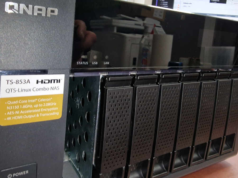 Serwer NAS QNAP TS-853A z widocznymi kieszeniami na dyski, etykietą specyfikacji i diodami statusu, sugerujący usługi związane z przechowywaniem i zarządzaniem danymi.