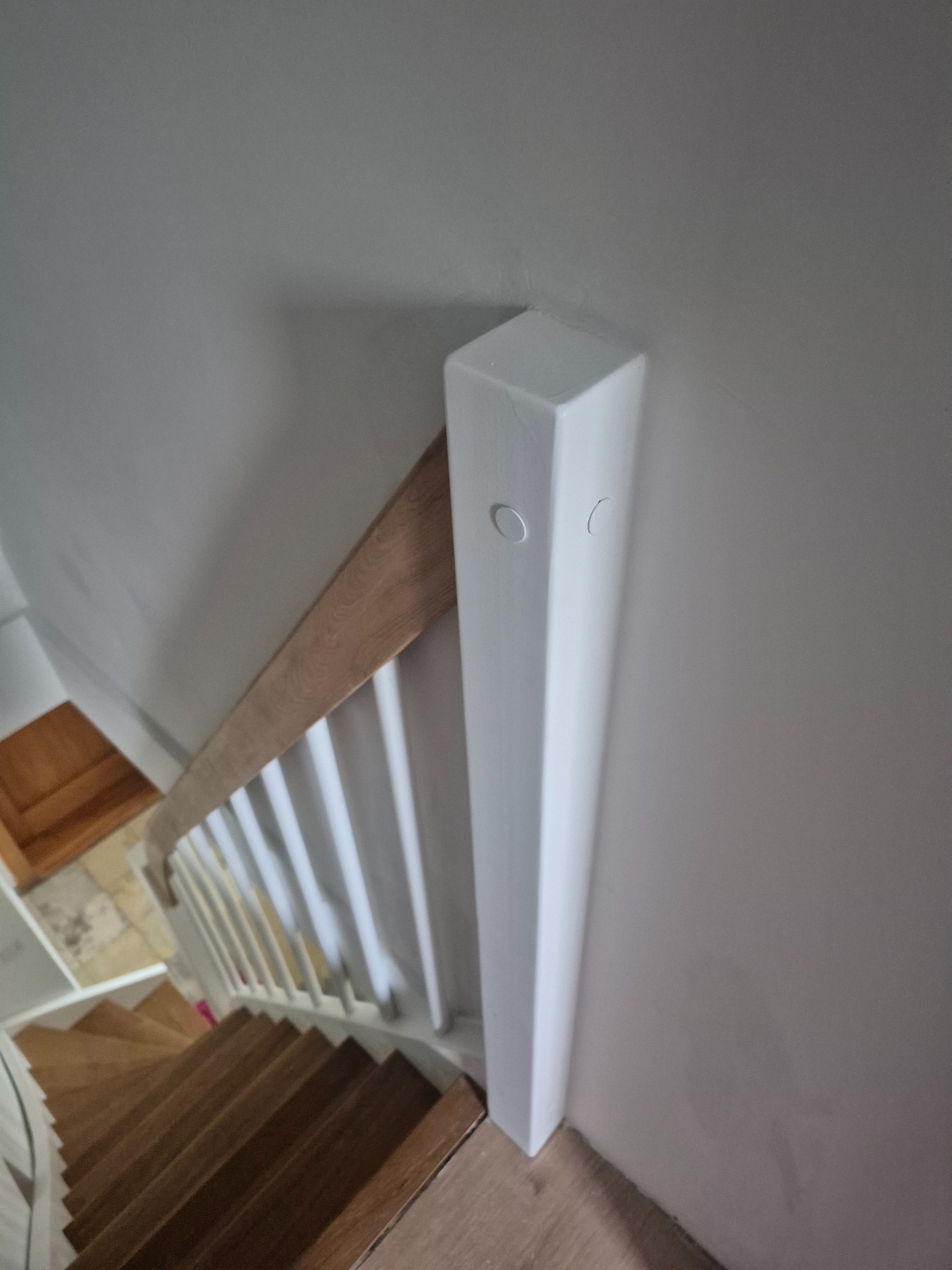 Biała balustrada schodowa z drewnianym poręczą, widok z góry na drewniane schody. Element wykończenia wnętrza, detale architektoniczne.