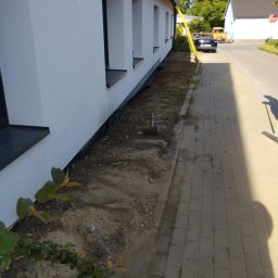 Babylon Mateusz Pytka - Ocieplony budynek z nową elewacją, widoczna warstwa izolacyjna przy gruncie i przygotowany teren pod nasadzenia. Świeżo pomalowana fasada w jasnym odcieniu.