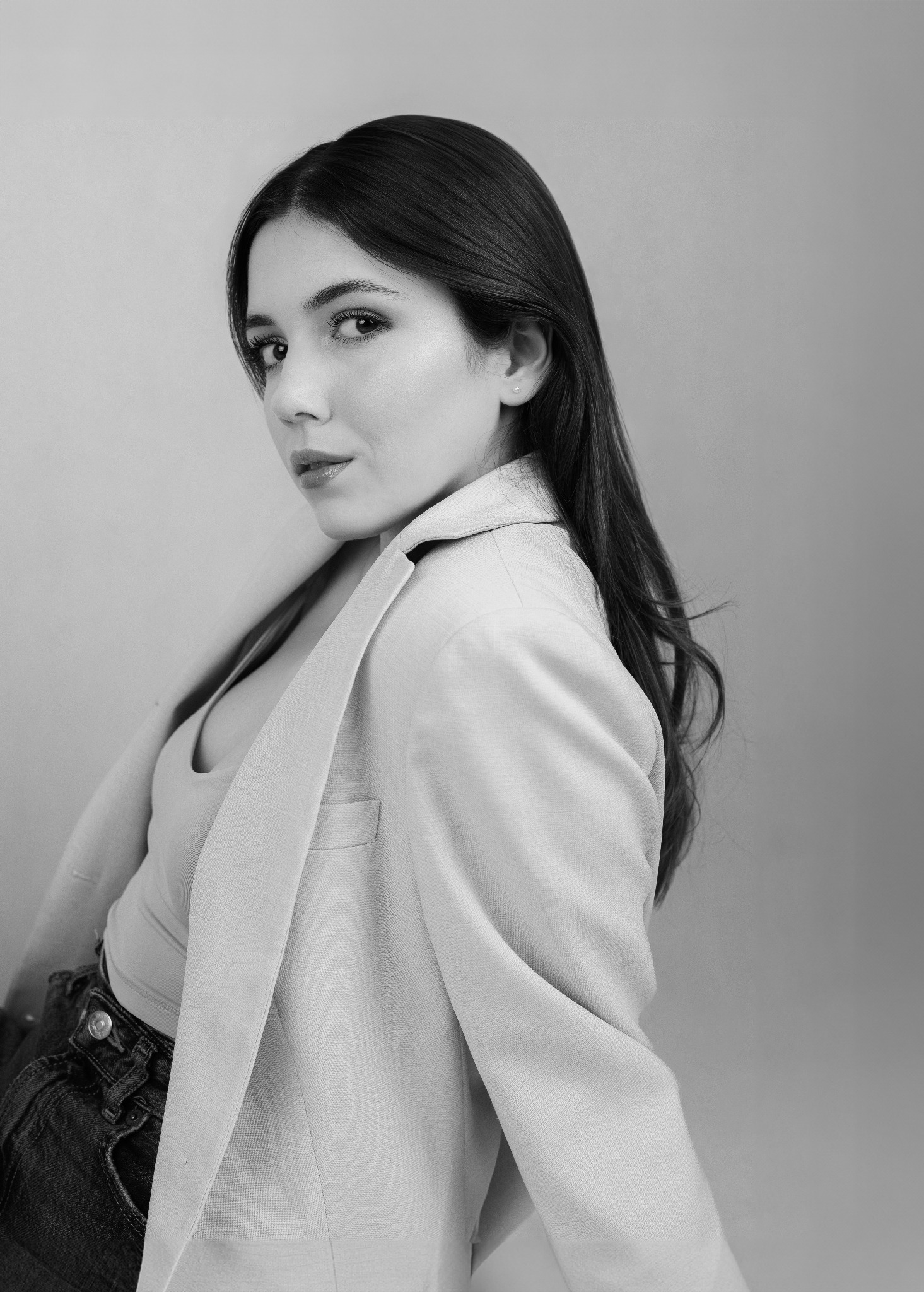 Portret kobiety w jasnym żakiecie, czarno-białe zdjęcie. Uwagę przykuwa jej spojrzenie skierowane w stronę widza i delikatny uśmiech. Minimalistyczne tło.