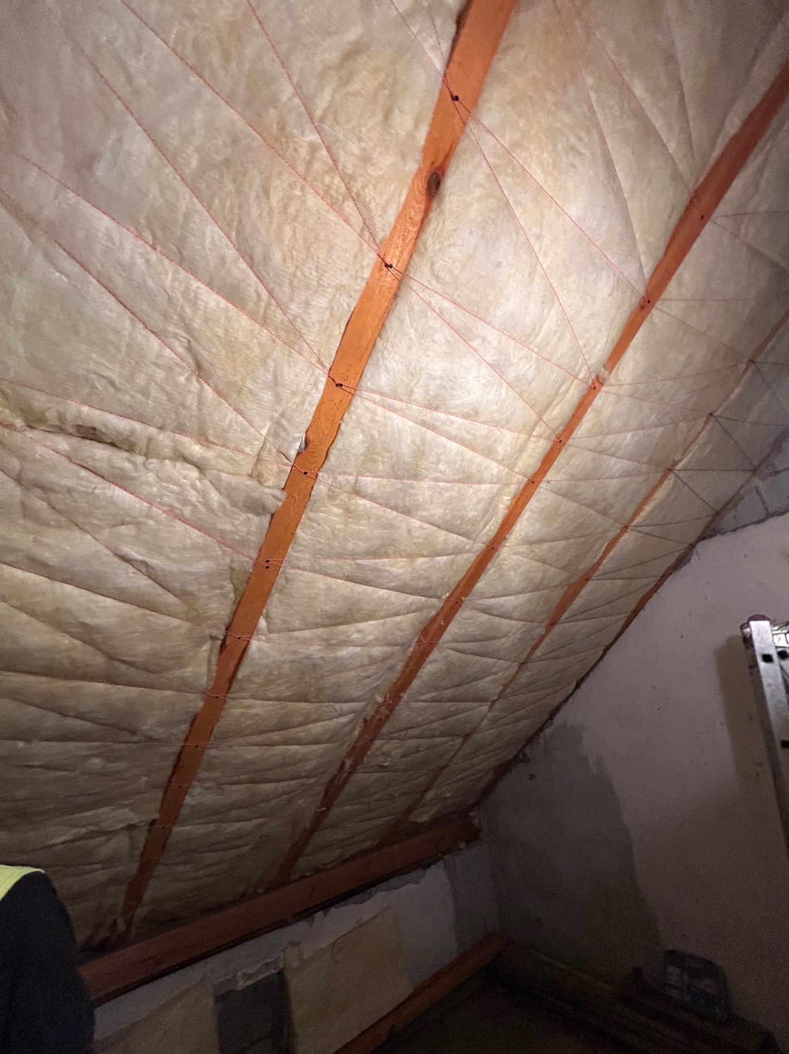 Ocieplenie poddasza wełną mineralną z widocznymi elementami konstrukcyjnymi w Myszyniec. Izolacja termiczna skośnego dachu z użyciem sznurka.