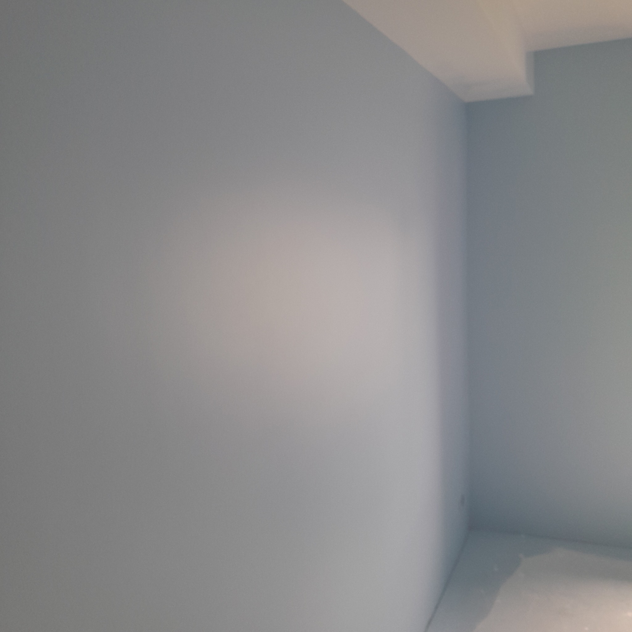 Świeżo pomalowane na jasny odcień niebieskiego ściany i sufit w rogu pokoju. Widoczne delikatne przejścia tonalne i gładka powierzchnia.