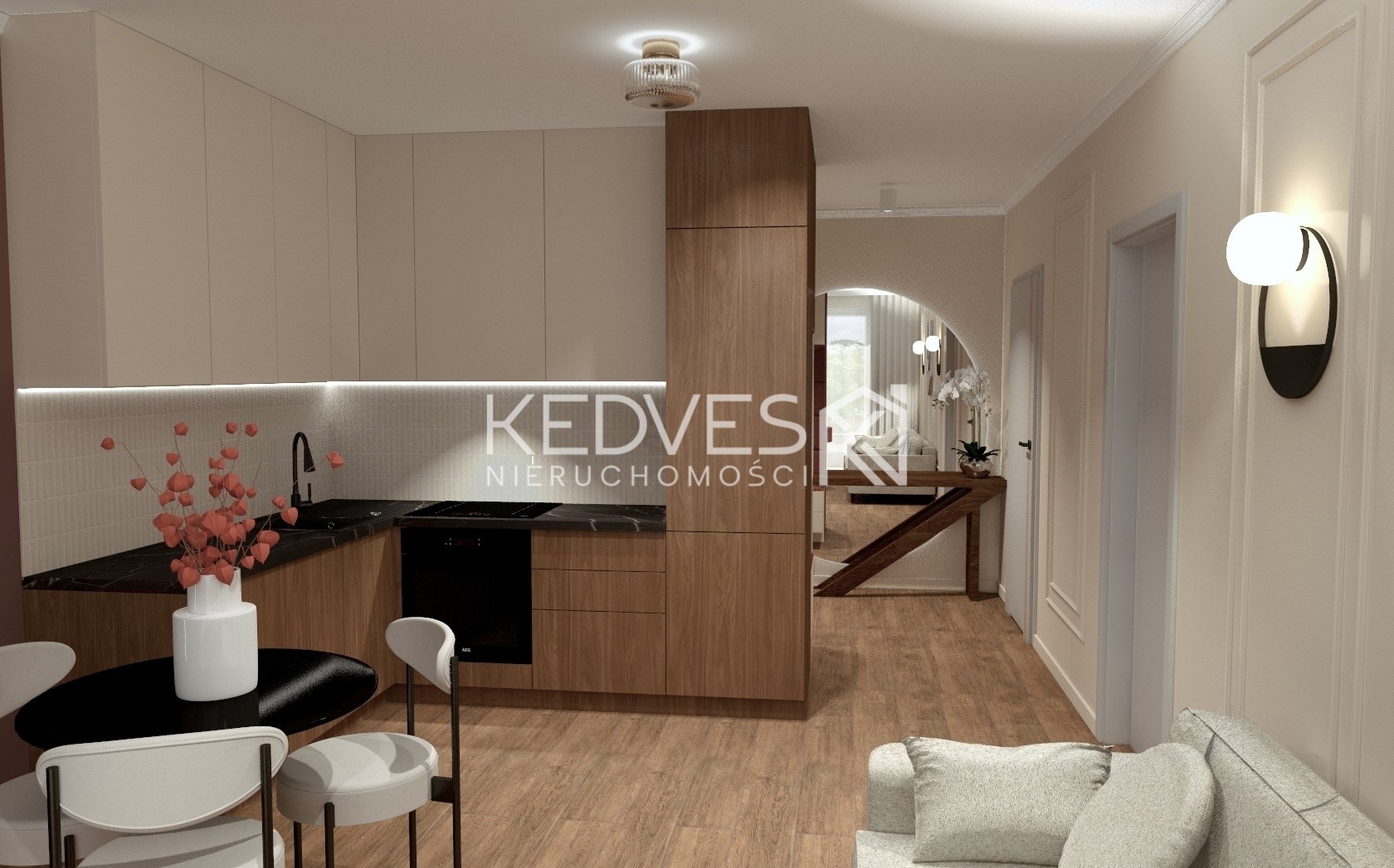 Wnętrze mieszkania: jasna kuchnia z drewnianymi szafkami, czarnym blatem i okrągłym stołem z kwiatami. W tle widoczny przedpokój z lustrem w kształcie łuku.