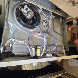 Mobilny Serwis AGD MSA - Adrian Bańdo - Wnętrze kuchenki z widocznymi elementami elektrycznymi i przewodami, sugerujące naprawę lub serwis. Widoczne transformatory i wentylator konwekcyjny.