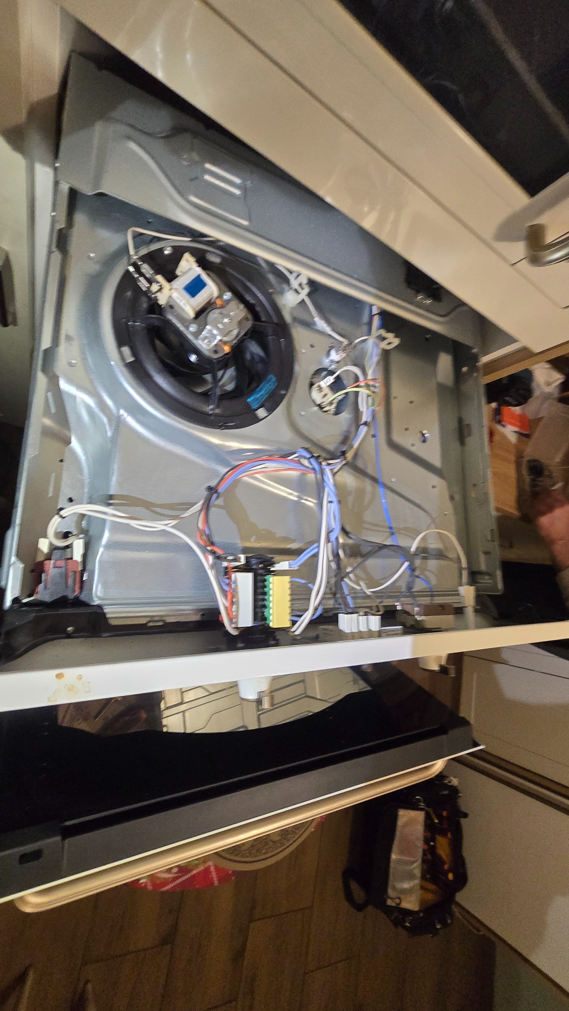 Wnętrze kuchenki z widocznymi elementami elektrycznymi i przewodami, sugerujące naprawę lub serwis. Widoczne transformatory i wentylator konwekcyjny.