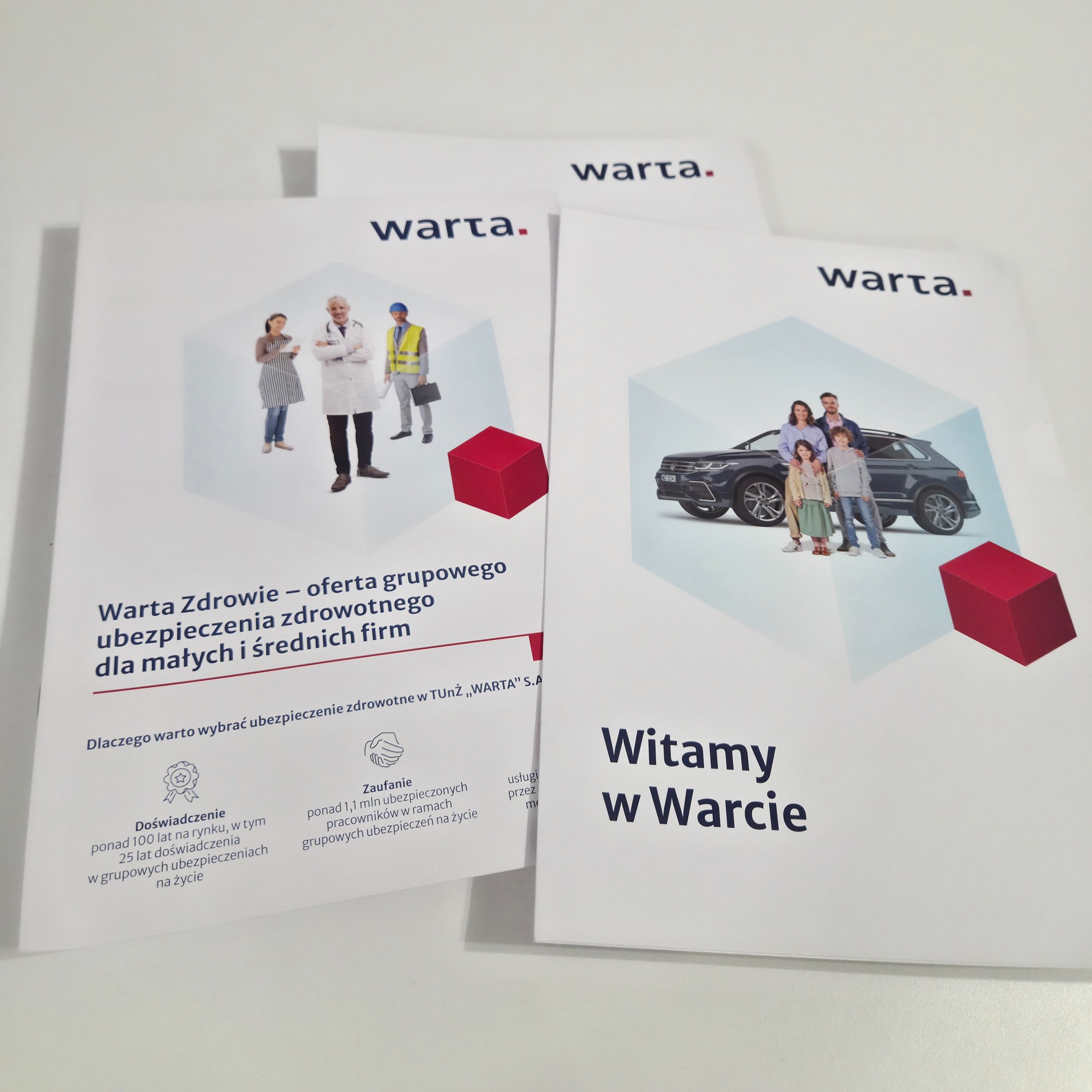 Ulotki Warta z ofertą ubezpieczeń grupowych i zdrowotnych dla firm, prezentujące doświadczenie i zaufanie. Czerwony sześcian w tle dodaje nowoczesności.