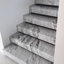 Granitex Tomasz Pietraszek - Granitowe schody wewnętrzne z szarym wzorem żyłkowania, widok z dołu, oświetlenie naturalne, minimalistyczny design.