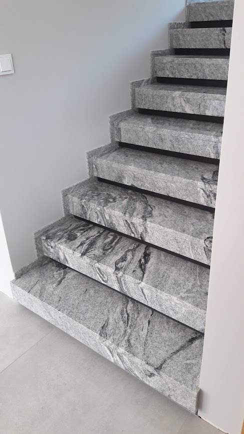 Granitowe schody wewnętrzne z szarym wzorem żyłkowania, widok z dołu, oświetlenie naturalne, minimalistyczny design.