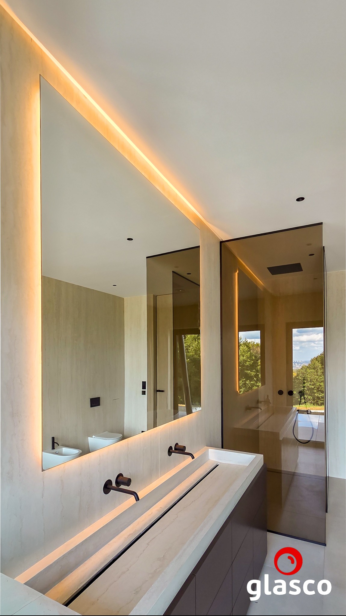 Nowoczesna łazienka z podświetlanym lustrem i kabiną prysznicową ze szkła barwionego w masie. Minimalistyczny design, armatura w kolorze czarnym.