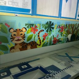 FP CONSTRUCTION - Kolorowa dekoracja ścienna z motywem dżungli i zwierząt (tygrys, panda) w pokoju dziecięcym, zabezpieczona taśmą malarską, z widocznymi szablonami na pierwszym planie.