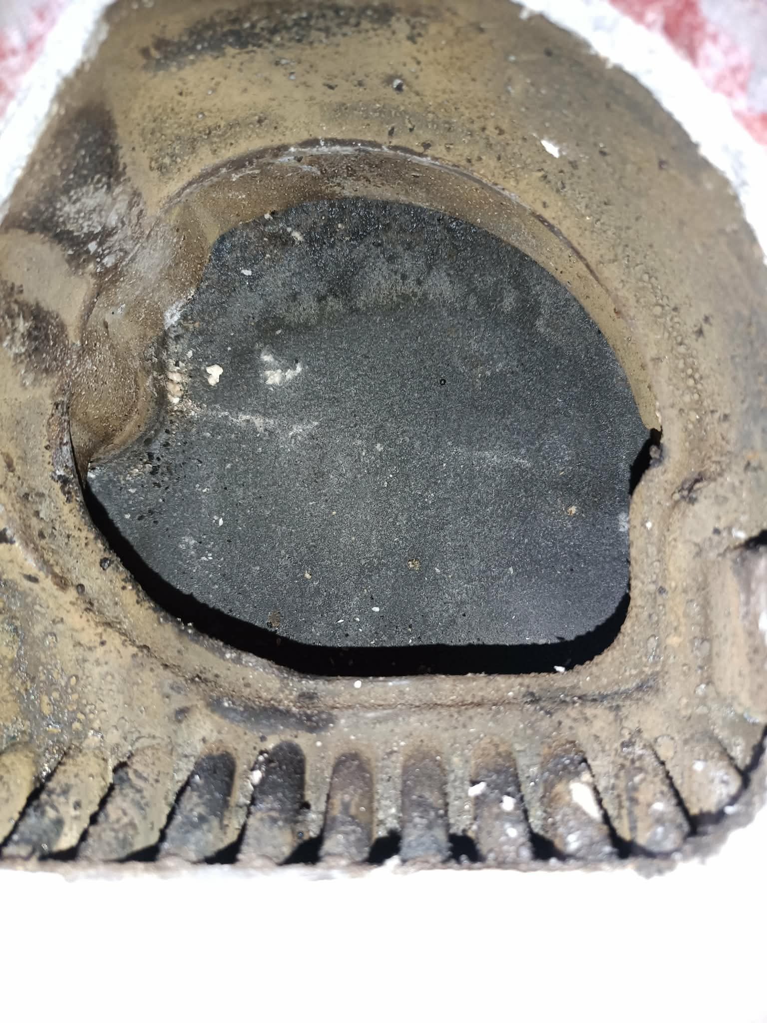 Zanieczyszczony palnik gazowy z widocznymi śladami korozji i nagaru, ukazujący zużycie elementu pieca gazowego. Detal z bliska.