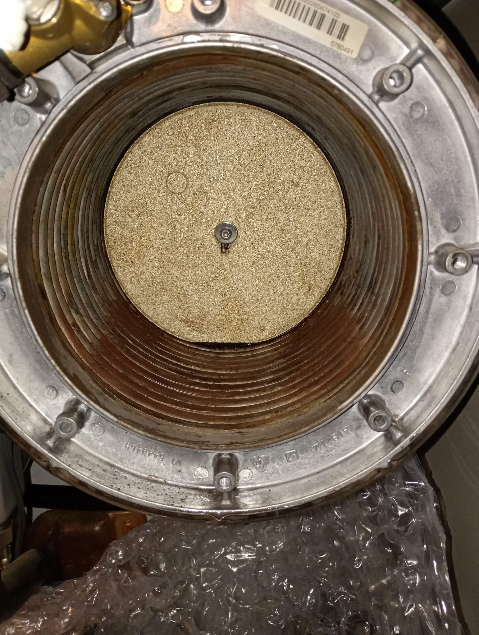 Wnętrze pieca gazowego z widocznym palnikiem i elementami konstrukcyjnymi. Widoczne ślady użytkowania i potencjalne zabrudzenia.