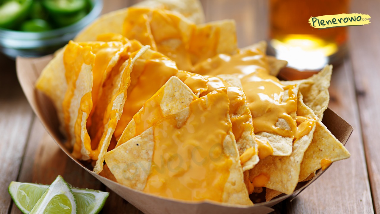 Nachos z serem cheddar i limonką w Pisarzowej, serwowane w tekturowej miseczce na drewnianym stole. W tle piwo i jalapeno.