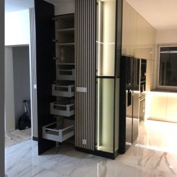 Woodsteel Pro Marcin Kamiński - Nowoczesna zabudowa kuchenna z otwartą szafką cargo i podświetleniem LED, widoczna na tle marmurowej podłogi. Minimalistyczny design z elementami drewna.