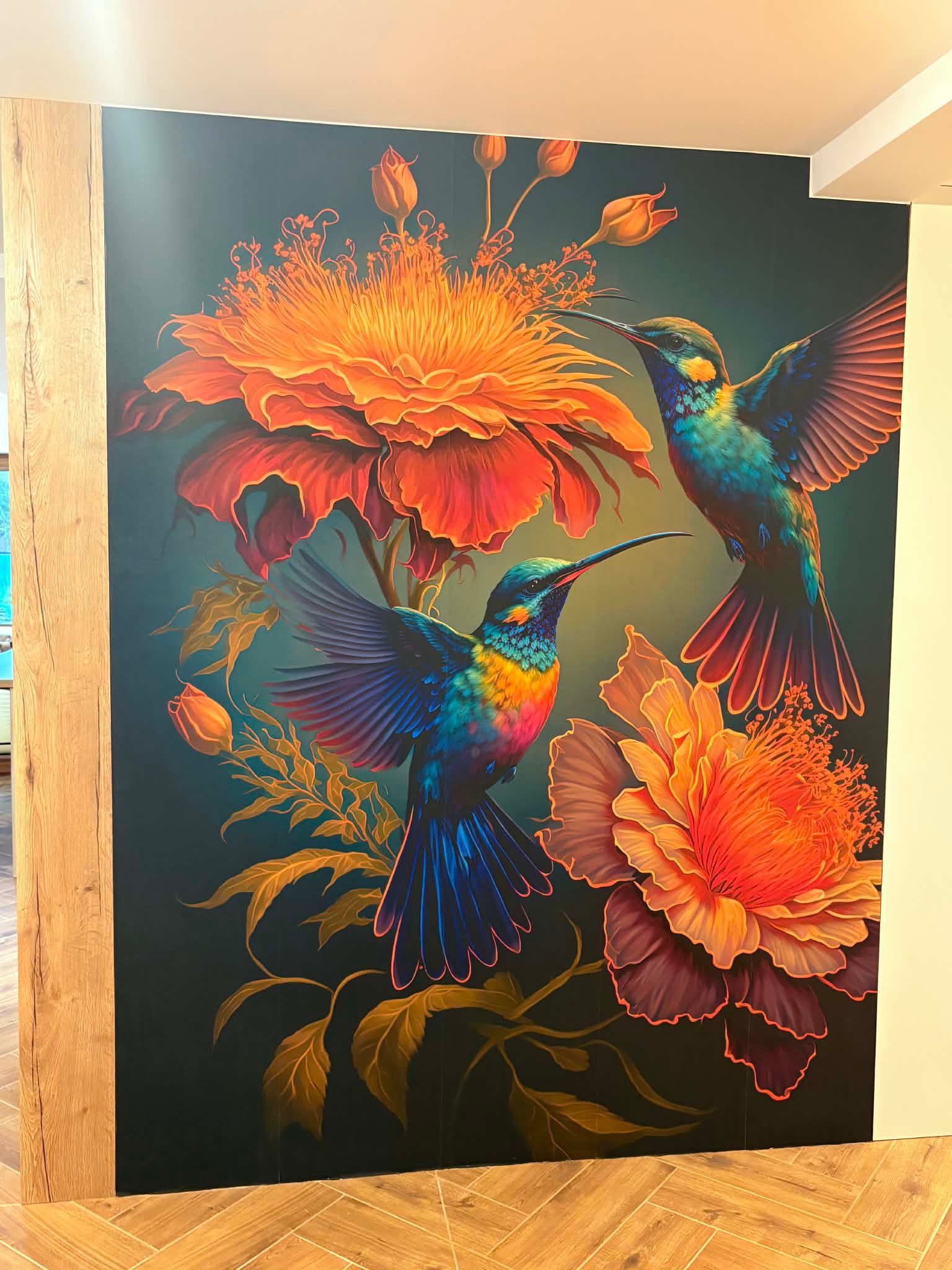 Ściana z fototapetą przedstawiającą kolibry i kwiaty w odcieniach pomarańczy i błękitu. Dekoracja wnętrza z drewnianymi elementami wykończeniowymi.