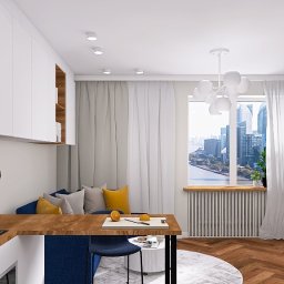 Wnętrze z sensem - Nowoczesne wnętrze mieszkania z aneksem kuchennym, drewnianym blatem i niebieską ścianą. Widok na miasto przez okno. Parkiet w jodełkę i designerska lampa.