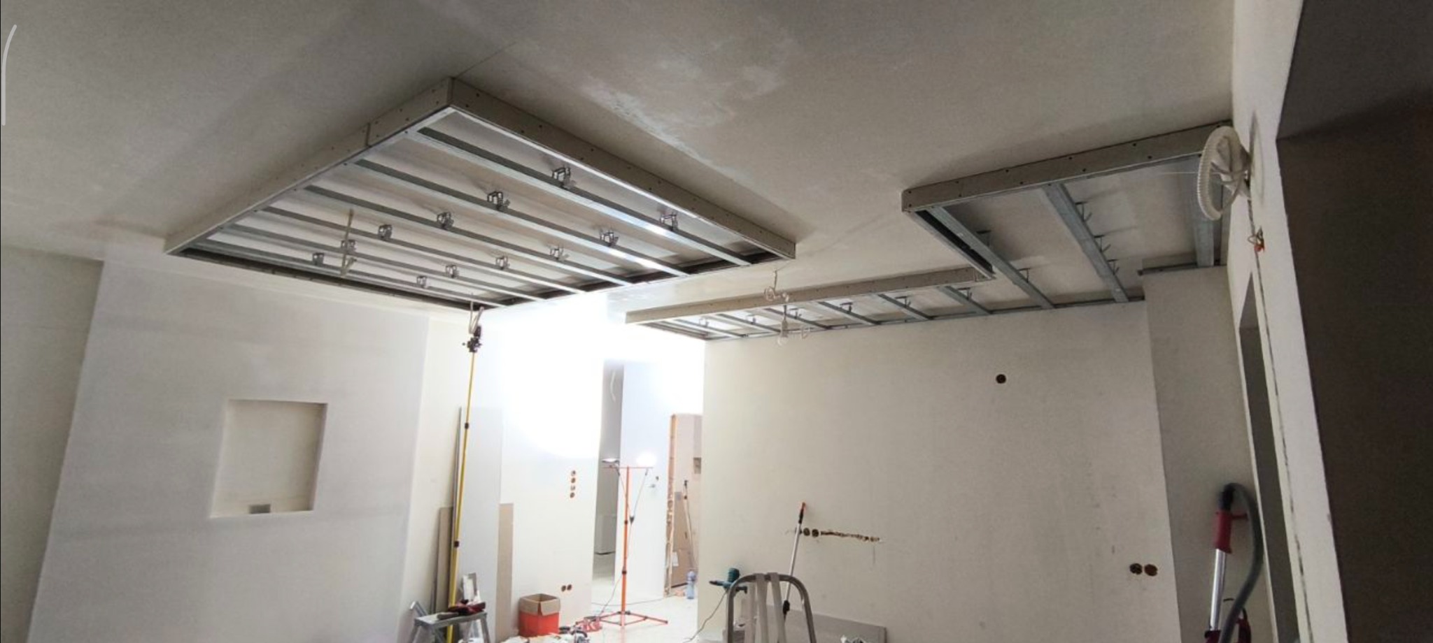 Montaż sufitu podwieszanego z płyt karton-gips w Częstochowie. Widoczne metalowe profile i konstrukcja nośna. Prace wykończeniowe w trakcie realizacji.