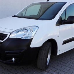POLMAR Marcin Puchalski - Biały, dostawczy Peugeot Partner z czarnym zderzakiem na kostce brukowej. Widok z przodu, lekko z boku. Auto czyste, zadbane, gotowe do transportu.
