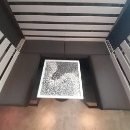 Michał Sikora - Nowoczesny zestaw mebli tapicerowanych z oryginalnym stolikiem z kamieniami, widok z góry. Stalowa konstrukcja i drewniane elementy tworzą unikalny design.