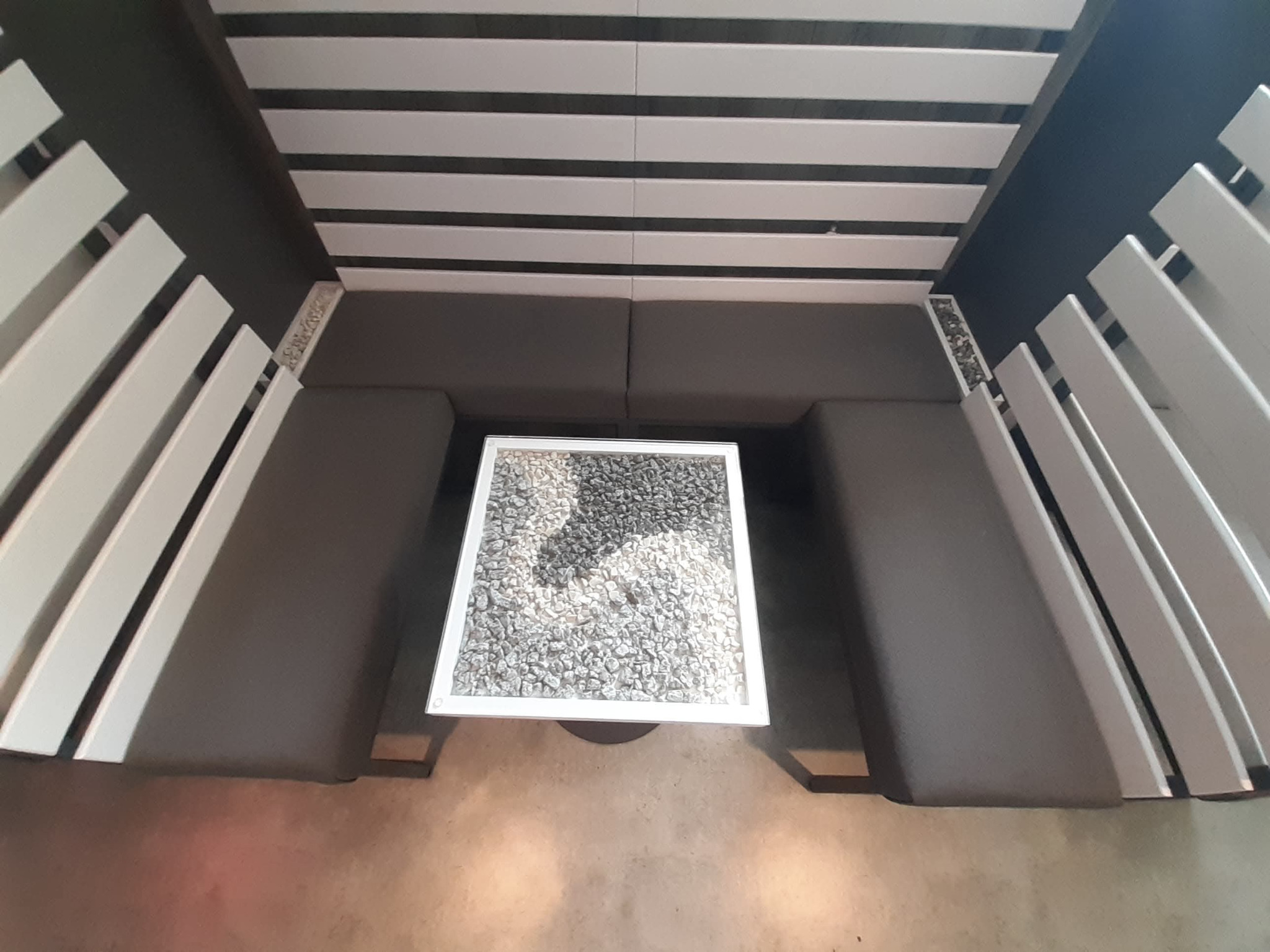 Nowoczesny zestaw mebli tapicerowanych z oryginalnym stolikiem z kamieniami, widok z góry. Stalowa konstrukcja i drewniane elementy tworzą unikalny design.