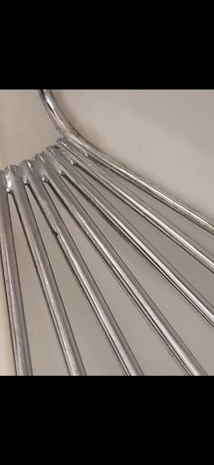 Metalowa szczotka do szorowania z widocznymi prętami i uchwytem, używana do czyszczenia powierzchni podczas sprzątania po remoncie.