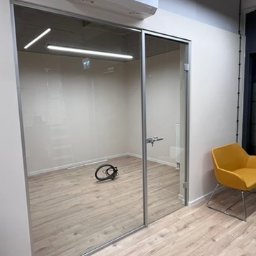 MODENA SPÓŁKA Z OGRANICZONĄ ODPOWIEDZIALNOŚCIĄ - Nowoczesne biuro z przeszkloną ścianą działową i żółtym krzesłem. Minimalistyczny design, jasne drewniane panele podłogowe, widoczne okablowanie.