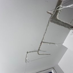 MODENA SPÓŁKA Z OGRANICZONĄ ODPOWIEDZIALNOŚCIĄ - Biały sufit z wystającymi przewodami elektrycznymi i fragmentem uszkodzonego narożnika, widoczne ślady po instalacji oświetlenia.