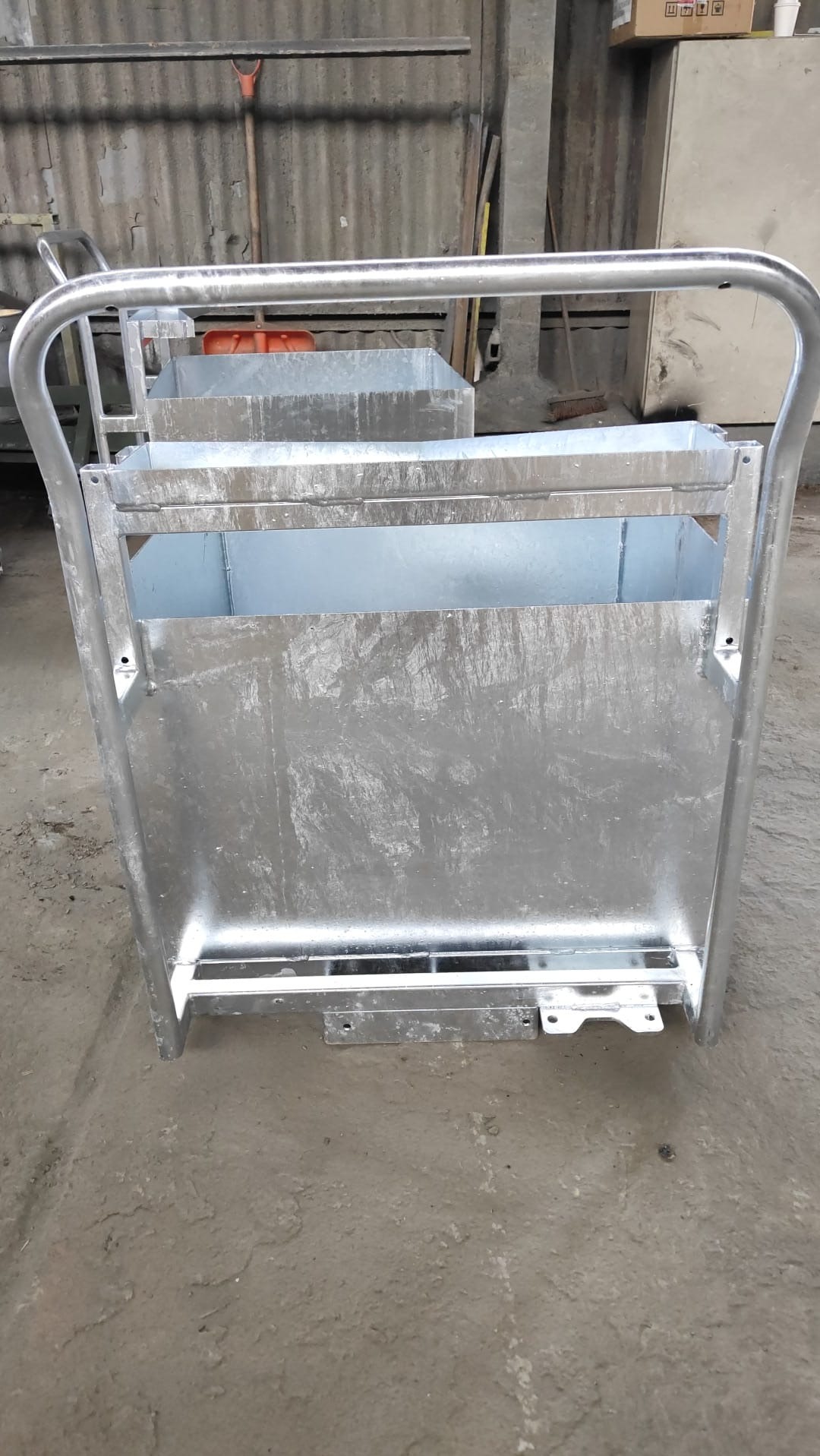 Metalowa konstrukcja w warsztacie, prawdopodobnie wózek transportowy lub element wyposażenia, wykonana ze spawanych profili i blach, surowe wykończenie.