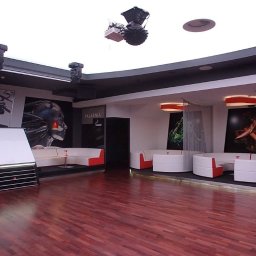 NOVA TECH CZESŁAWA GEMBROWICZ - Nowoczesne wnętrze klubu z parkietem, białymi sofami i futurystycznymi dekoracjami. Oświetlenie punktowe i grafiki na ścianach tworzą unikalny klimat.