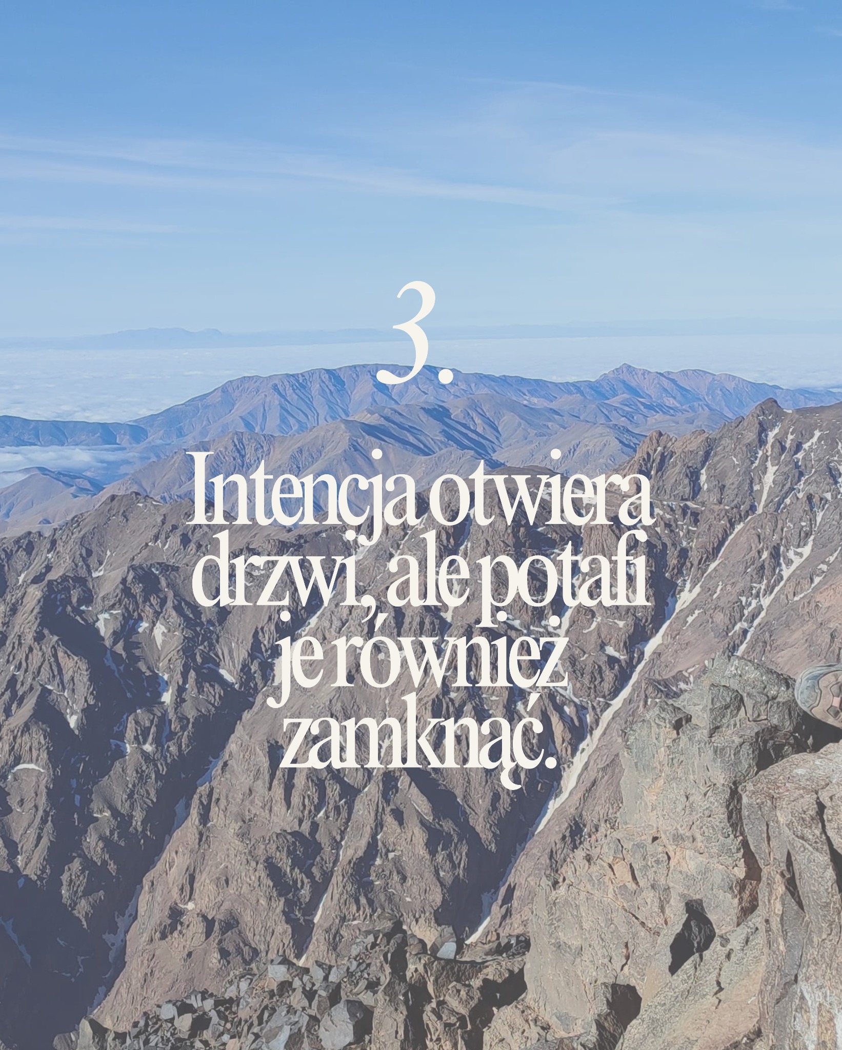 Górzysty krajobraz z widocznym tekstem motywacyjnym w kolorze białym. W tle błękitne niebo i szczyty górskie. Ujęcie z góry.